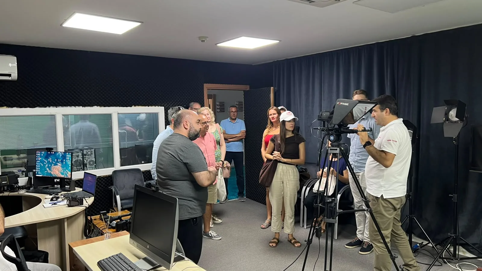 Participants being shown a tripod-mounted camera and filming setup in Adana TAYEM's recording space