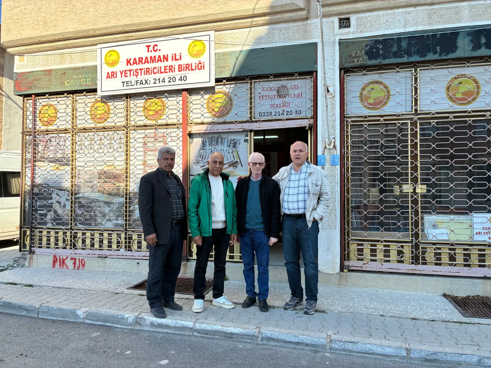 Four participants outside the Karaman Provincial Beekeepers' Union, with the union's sign above them