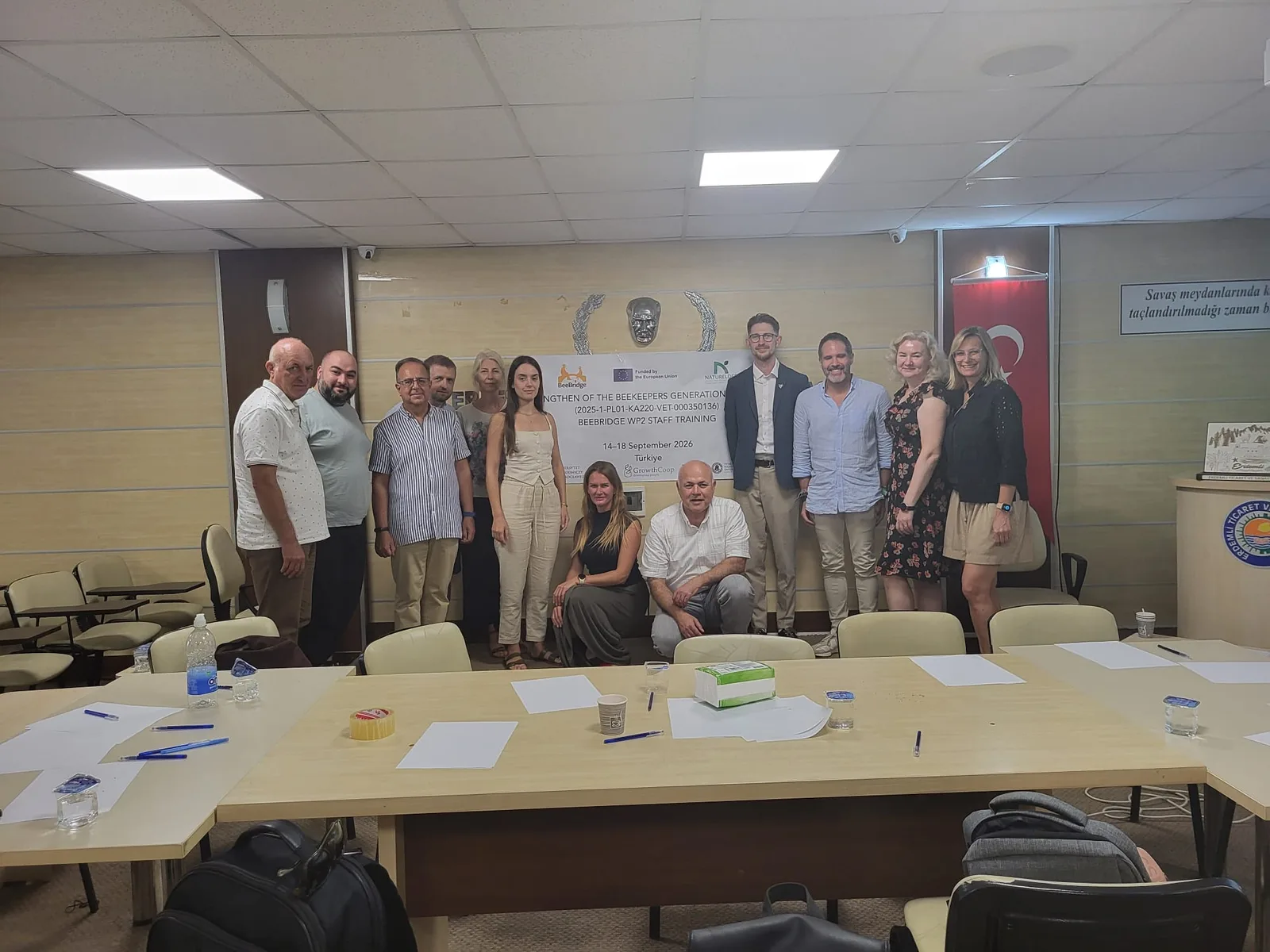BeeBridge staff training participants in a meeting room in front of the project banner