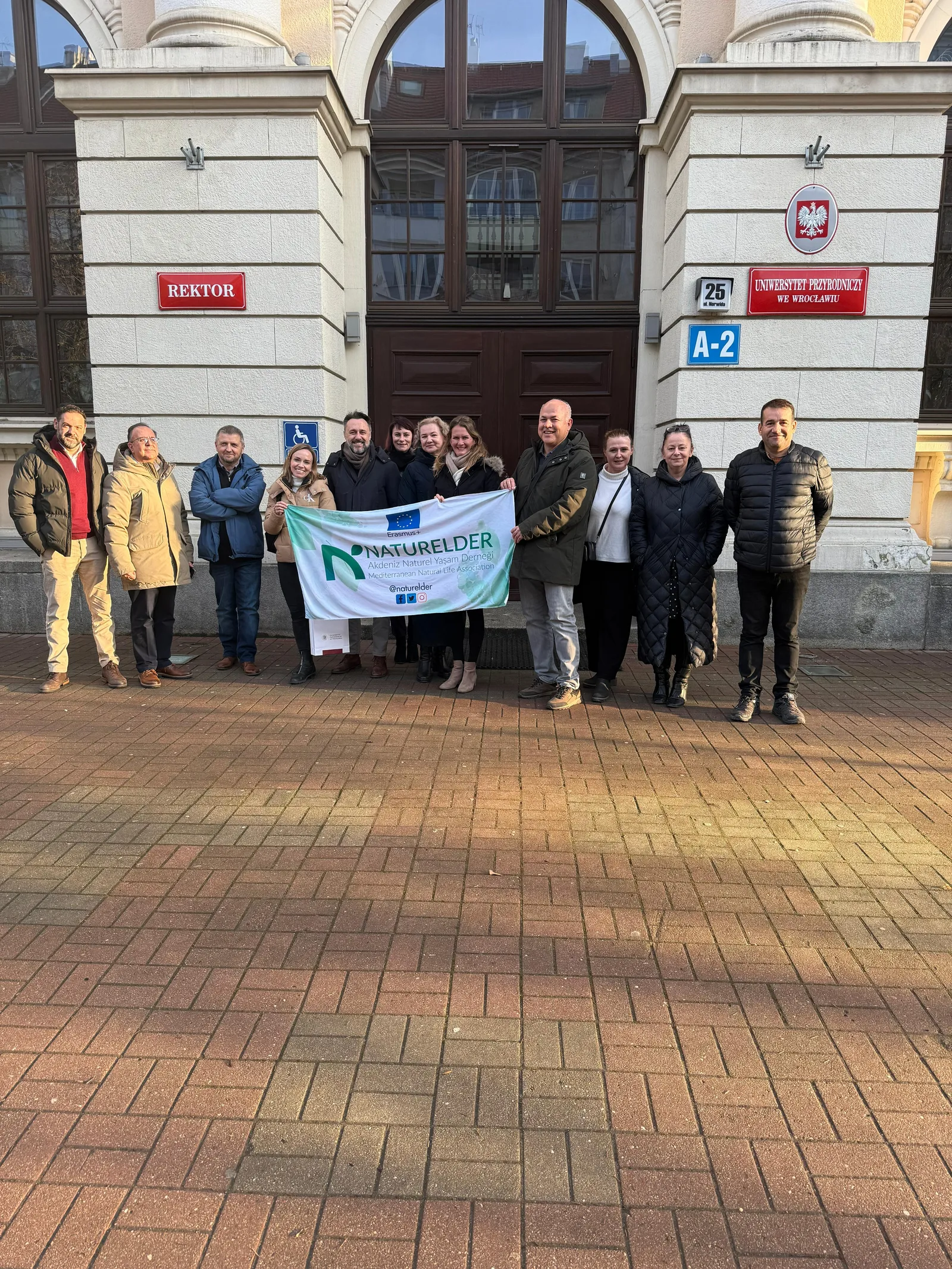 BeeBridge project partners with a NATURELDER banner outside Wrocław University of Environmental and Life Sciences