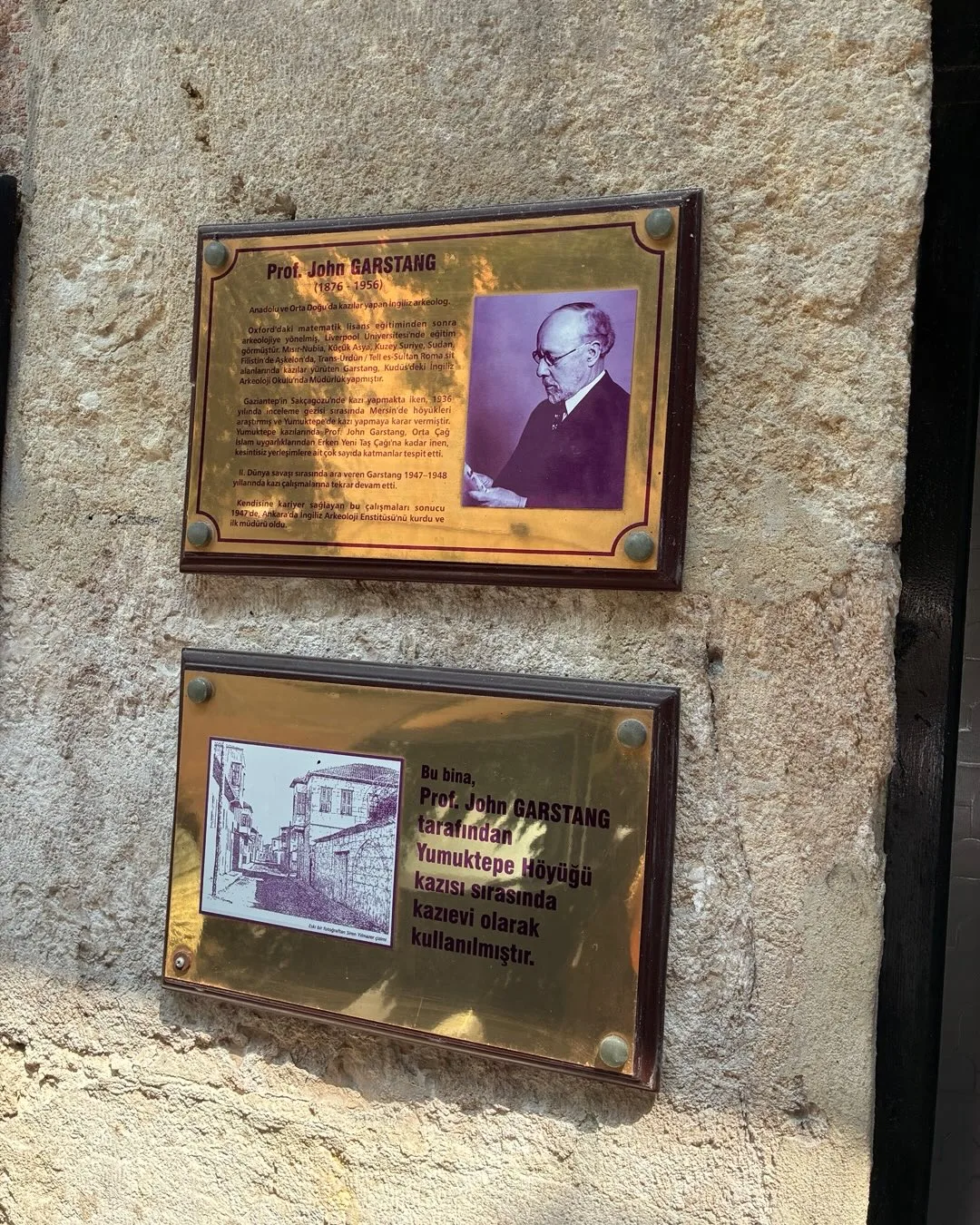 Plaques on a stone wall about John Garstang and the building's use as an excavation house