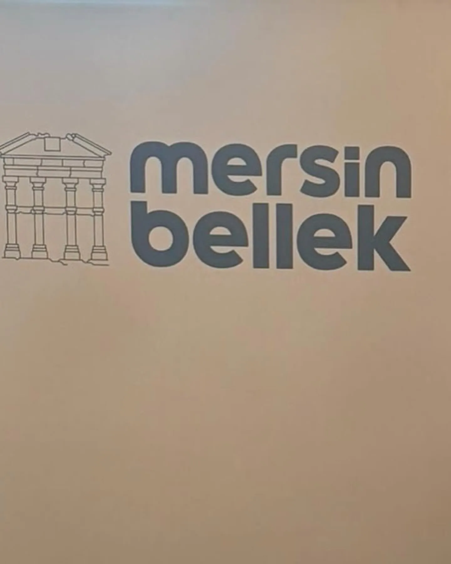 A sign bearing the words Mersin Bellek and an illustration of a historic building