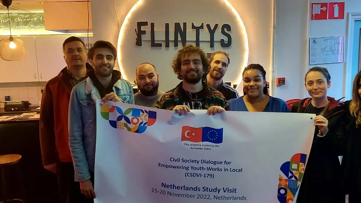 Participants holding the Netherlands study visit banner in front of a Flintys sign