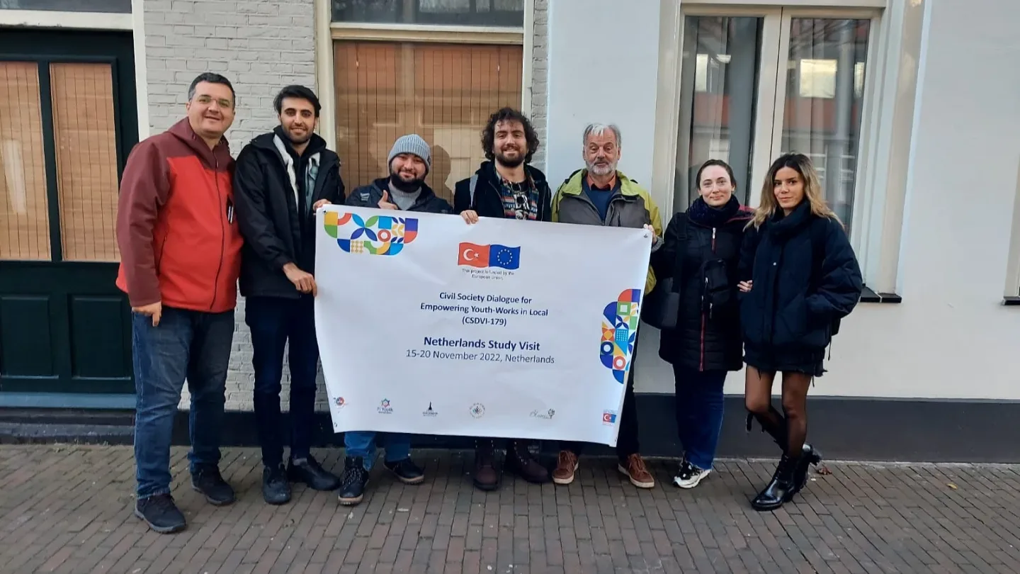 Study visit participants holding the project banner outside a building in the Netherlands